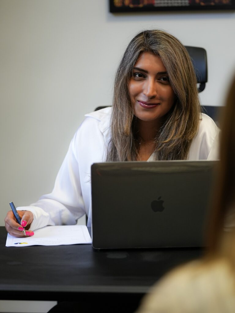 Mona Haratianfar smiling and taking notes during a consultation at her desk